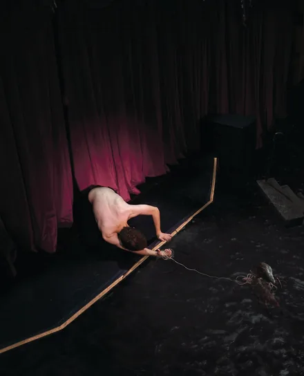 brakence leaning over the edge of a dark stage in front of red curtains, the photo from the VIP site